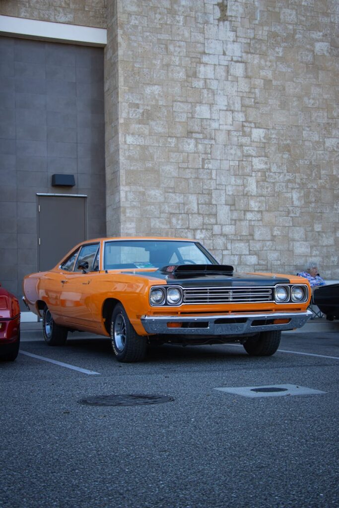 Classic orange Plymouth Road Runner parked in an urban setting, showcasing vintage muscle car design.