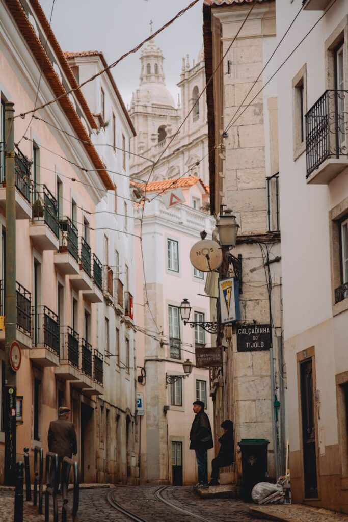 Explore a quaint Lisbon alley with tram rails and a view of the São Vicente de Fora monastery.