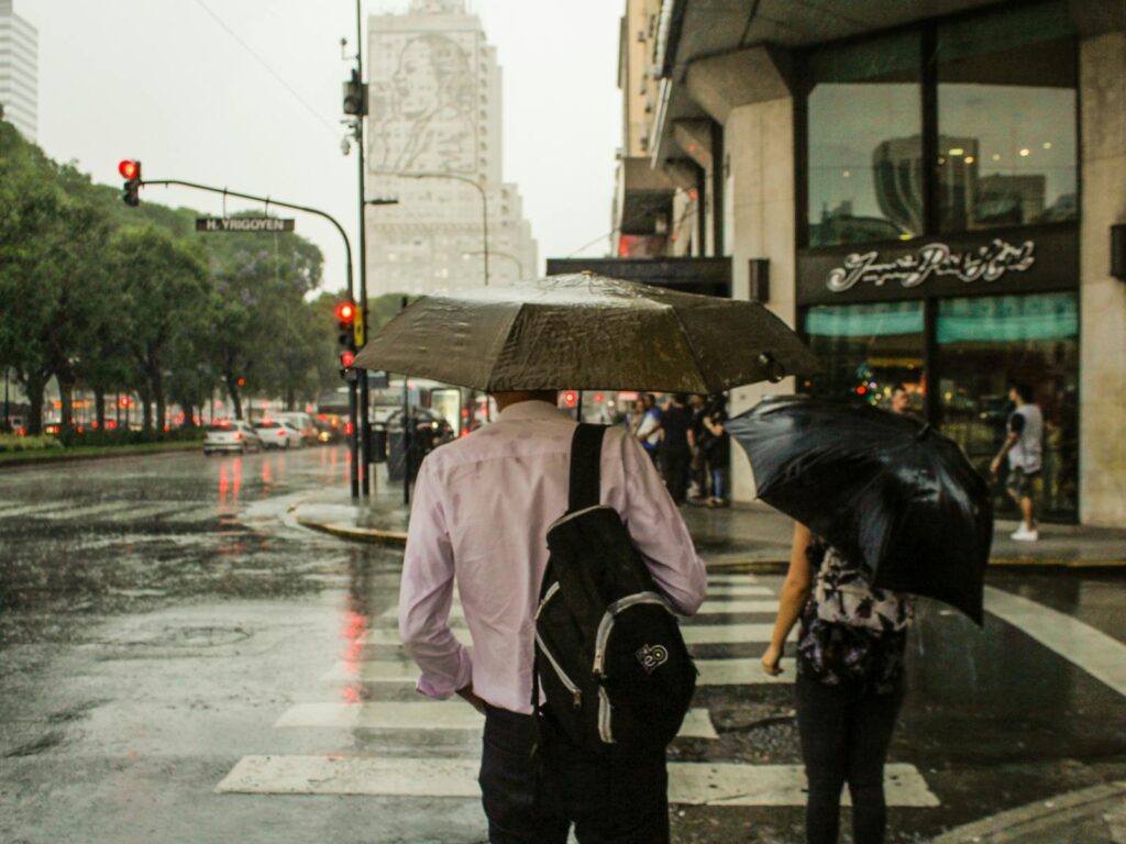 Pedestrians with umbrellas crossing the street on a rainy day in Buenos Aires, Argentina.