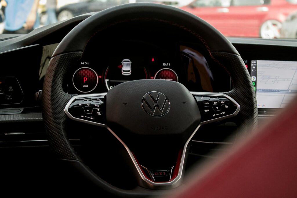Close-up of a modern Volkswagen car steering wheel with digital dashboard.