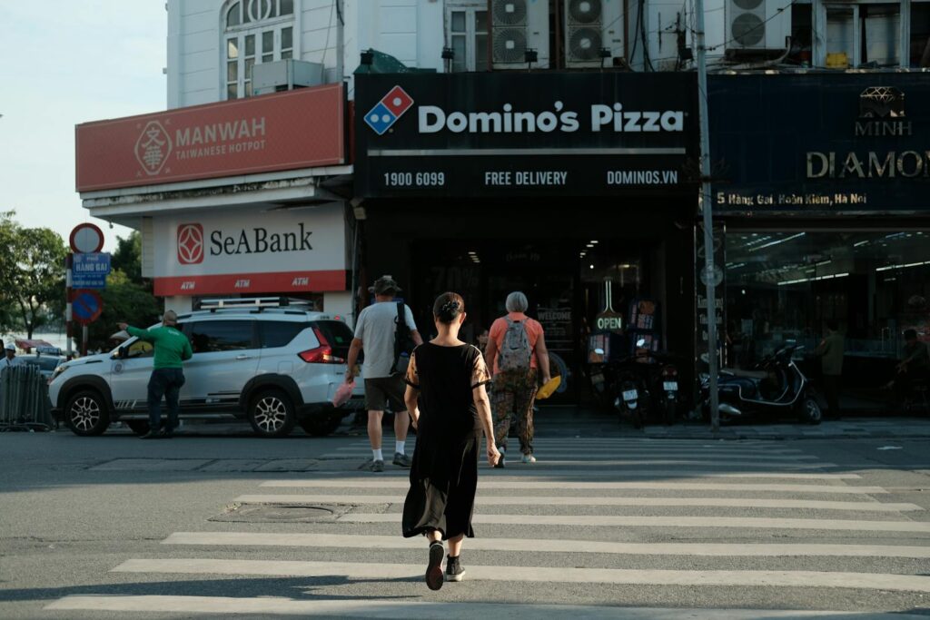 A woman crosses the street near Domino's Pizza in Hanoi, Vietnam.