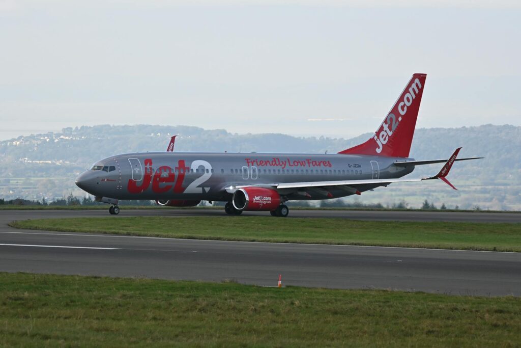 Jet2 passenger airplane taxiing at Bristol Airport with scenic backdrop.