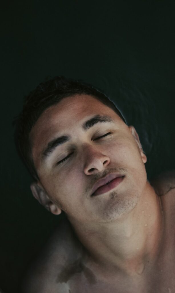 a man laying in a bathtub with his eyes closed