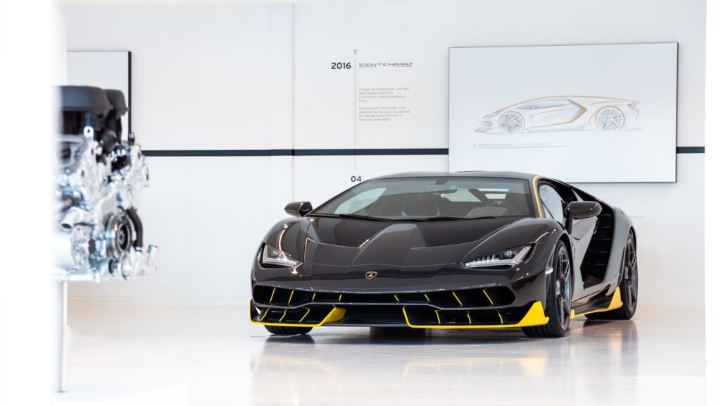 Black and yellow Lamborghini Centenario displayed in an automotive museum, showcasing luxury design.
