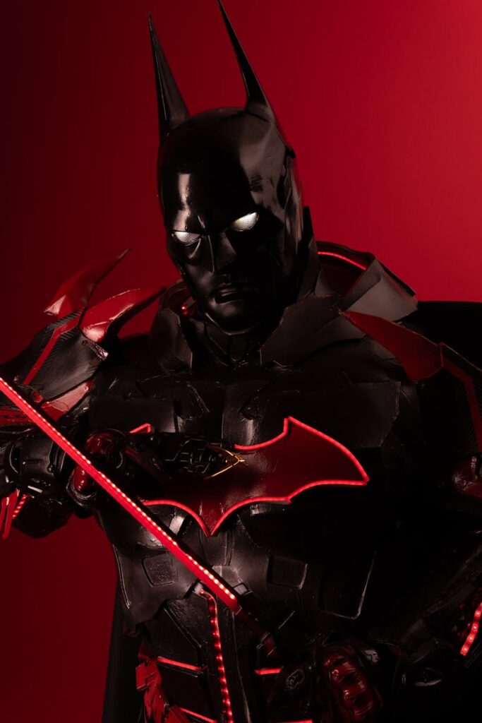 Dramatic portrait of a person in black and red Batman cosplay against a red background.