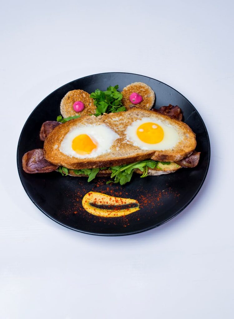 Playful breakfast plate featuring eggs fried in bread with decorative garnishes.