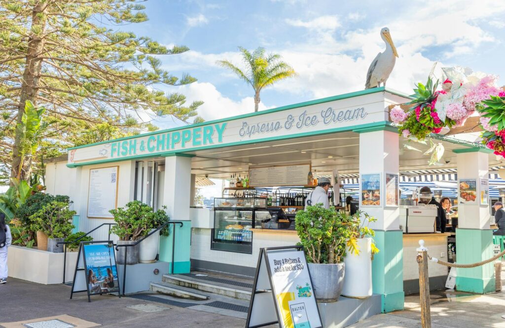 Bright and inviting fish and chip shop with outdoor seating under a clear sky.