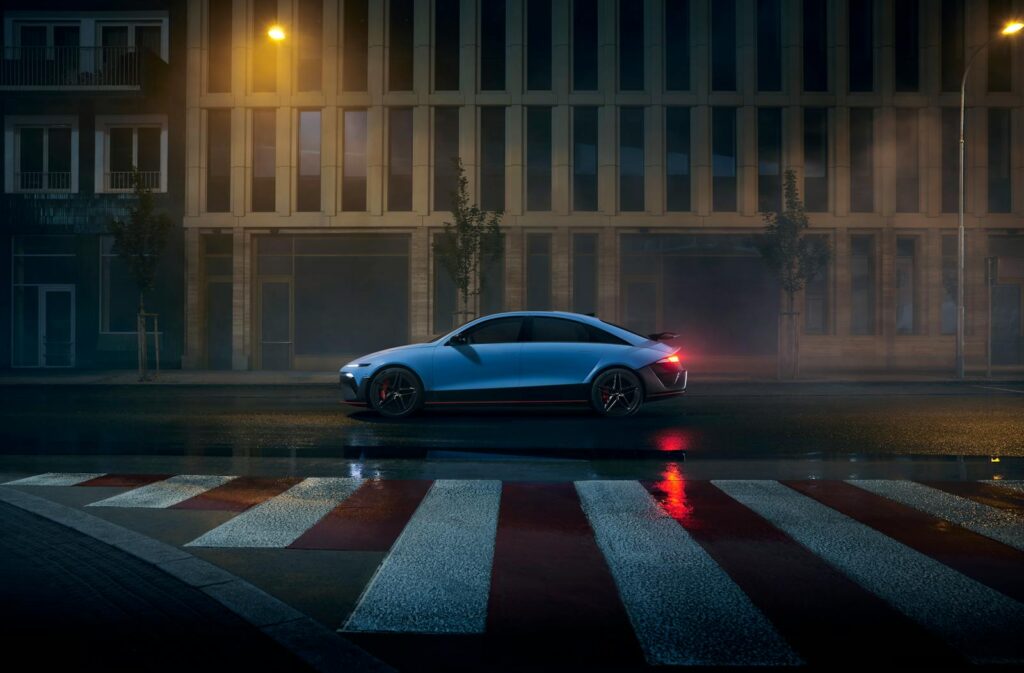 Modern electric vehicle parked on a wet city road under streetlights at night.
