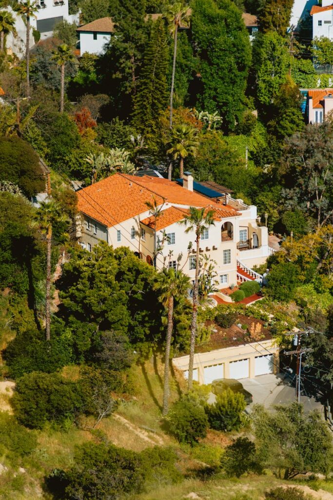 Aerial view of a Mediterranean-style villa surrounded by dense greenery and palm trees.