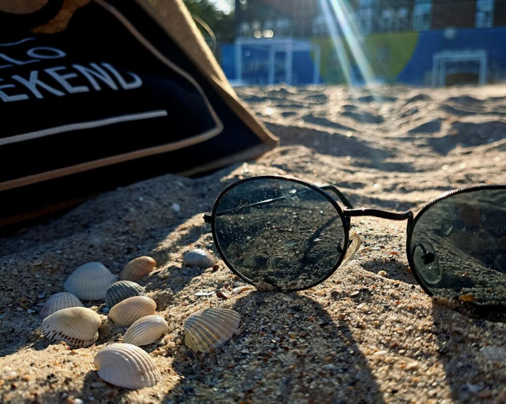 Sunglasses and shells on a sandy beach, capturing summer vibes and relaxation.
