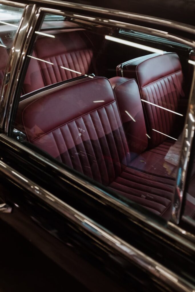 Close-up view of a classic car interior featuring red leather seats and chrome details.