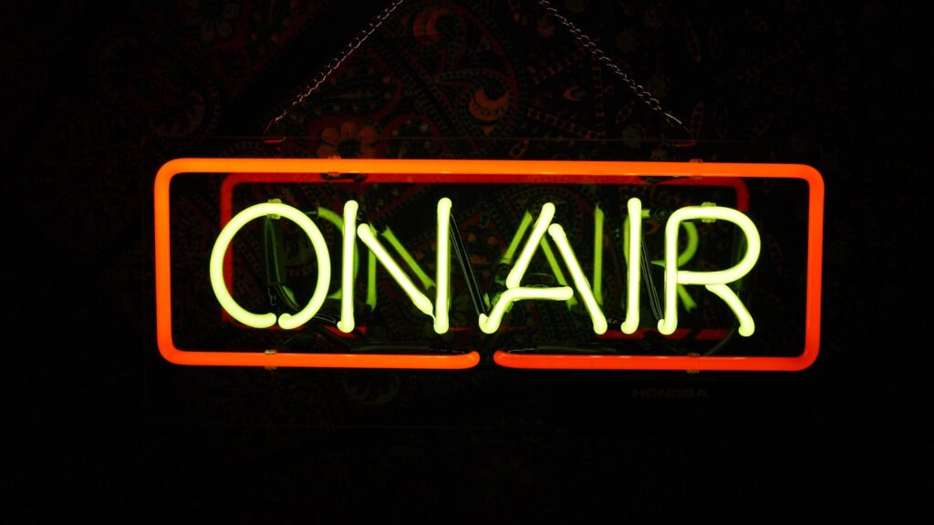 a neon sign that says on air hanging from a chain