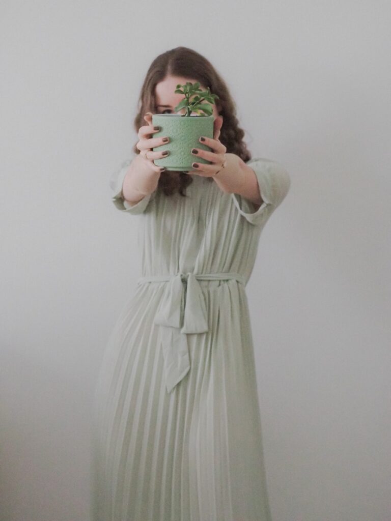 a person in a white dress holding a green cup