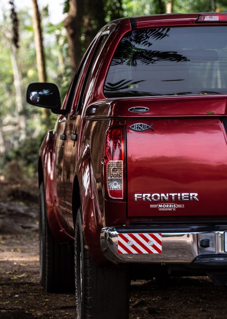 Close-up of a red Frontier pickup truck parked outdoors in Ghana's wilderness.