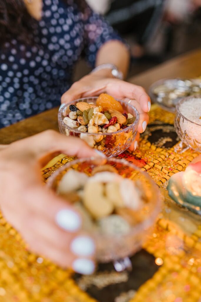A close-up of hands holding glass bowls filled with assorted nuts and dried fruits.