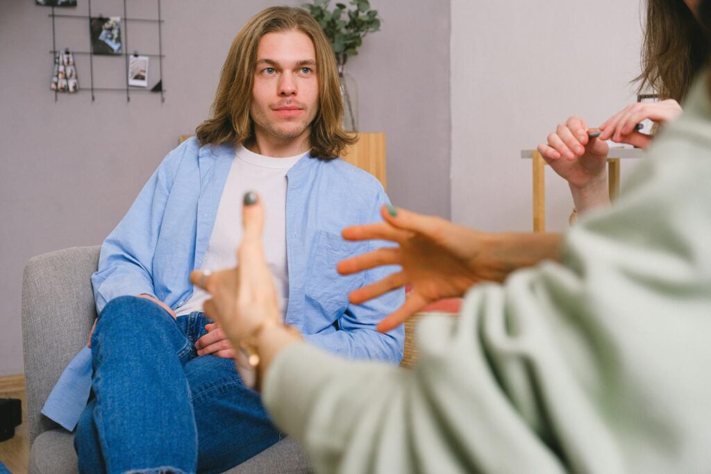 A man listens attentively as his partner gestures during a counseling session indoors.