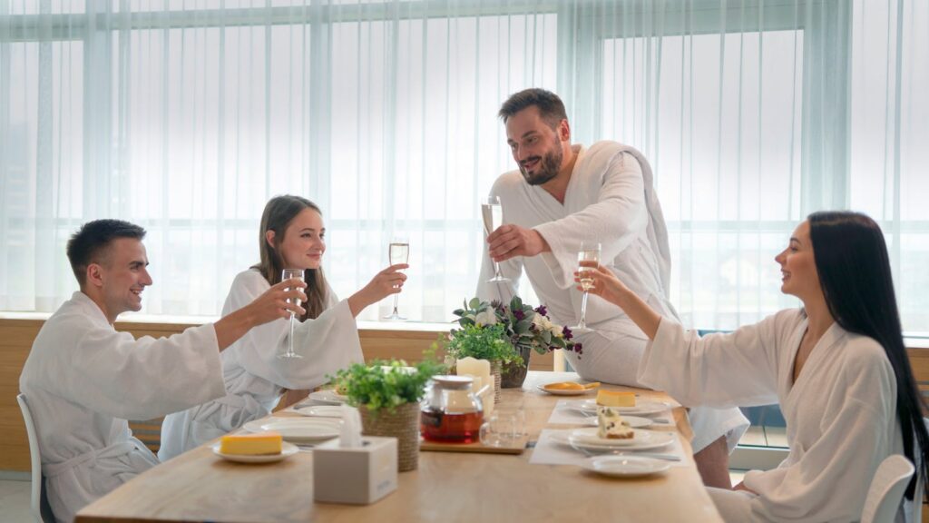 Group of friends in bathrobes enjoying drinks and self-care indoors. Relaxation and togetherness.