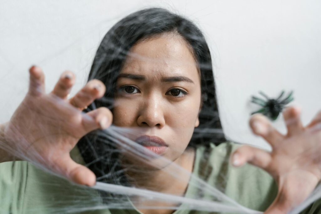 A woman faces anxiety symbolized by a spider web, conveying emotions of fear and entrapment.