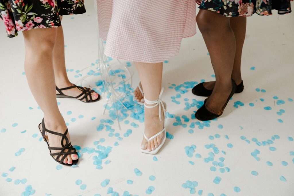 Women's legs in elegant footwear surrounded by blue petals, showcasing style and fashion.