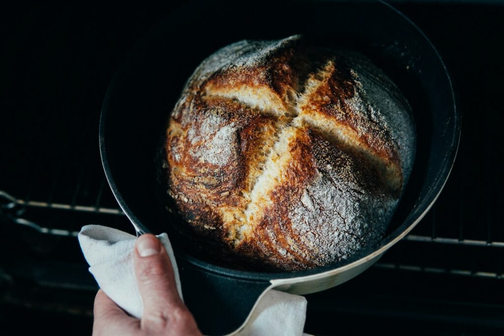 person holding a black round tray with brown bread