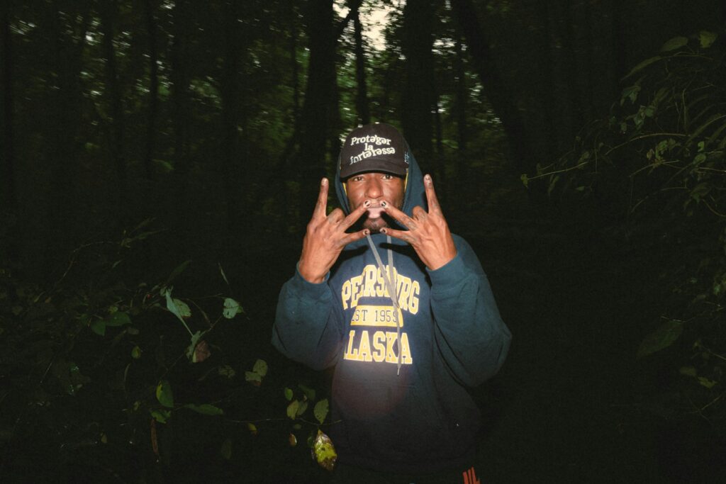 a man standing in the middle of a forest holding his hands up to his face