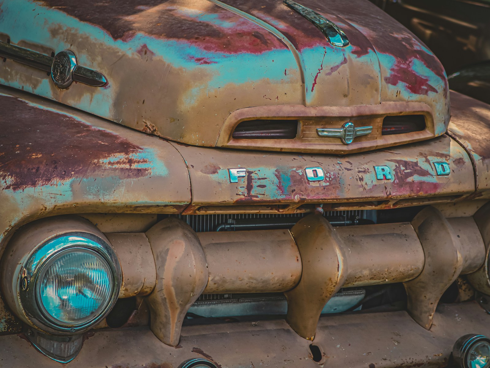 A rusted old car is sitting in a junk yard