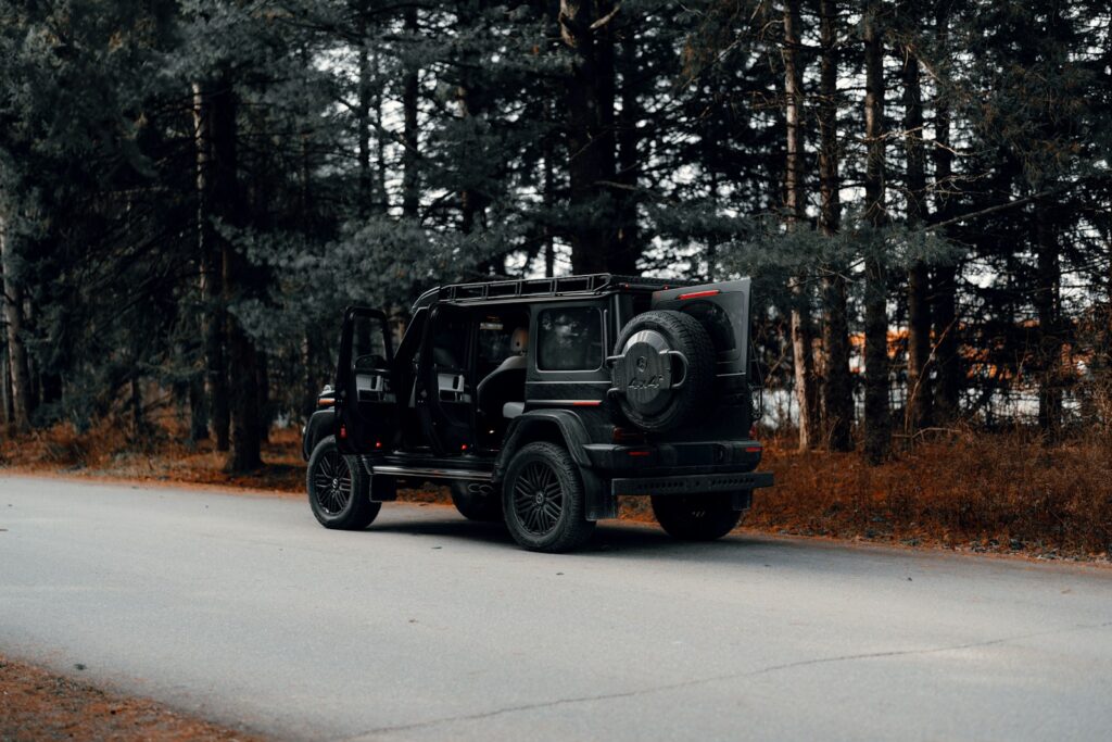 A black jeep driving down a road next to a forest