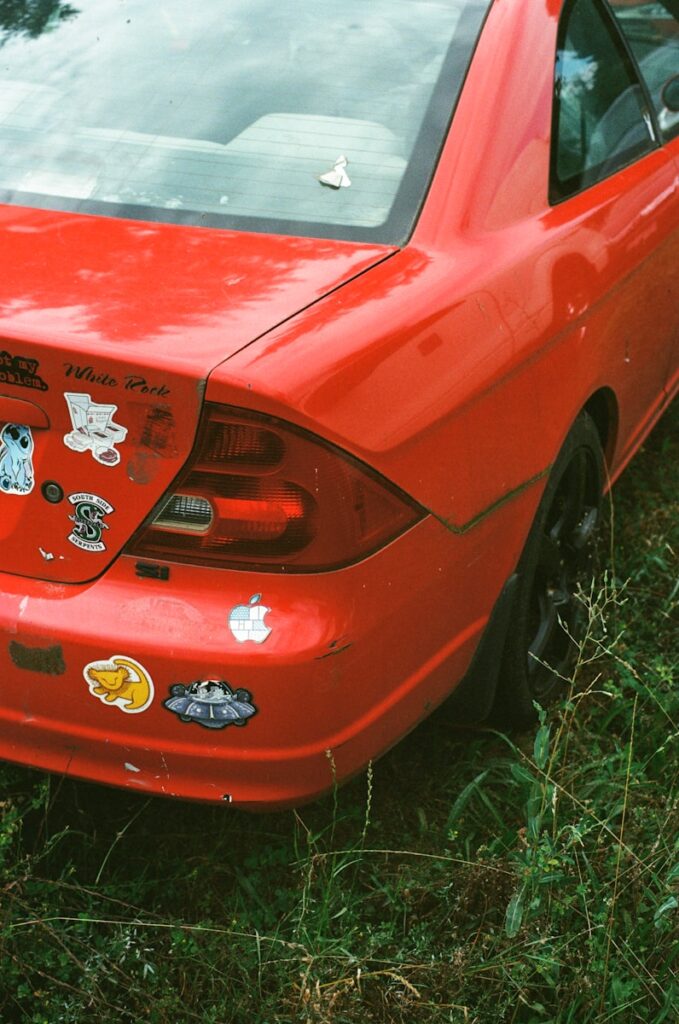 A red car that has stickers on it
