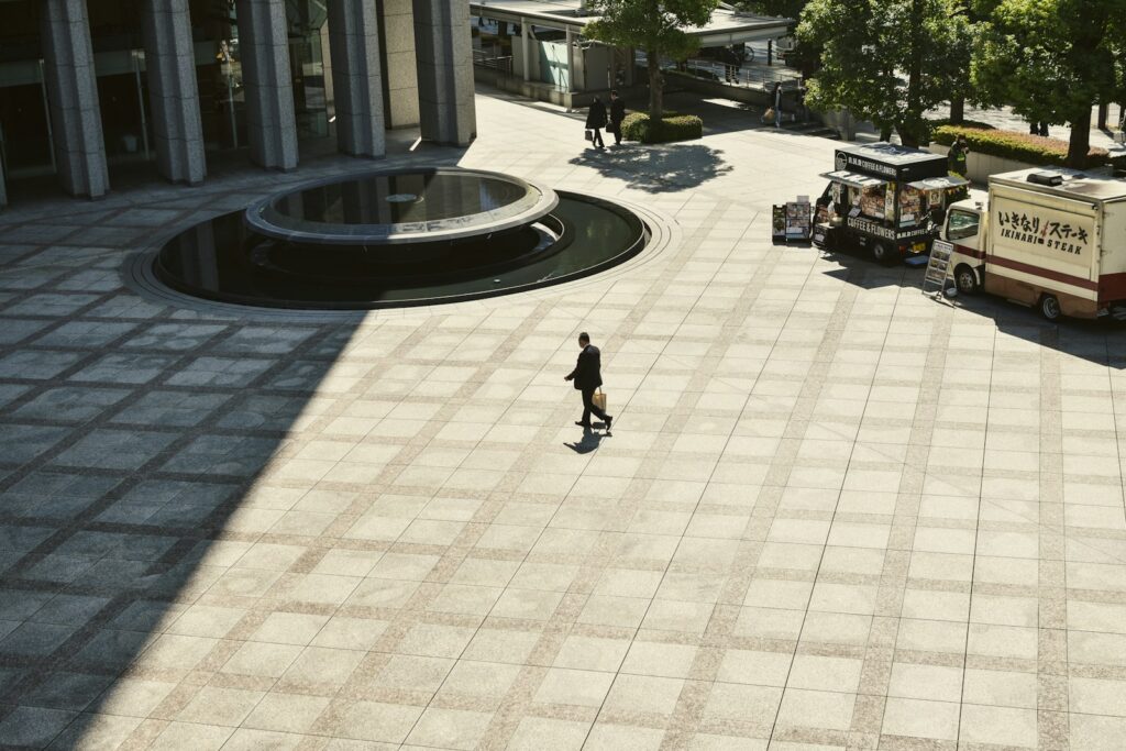 A person walks across a large, empty plaza.