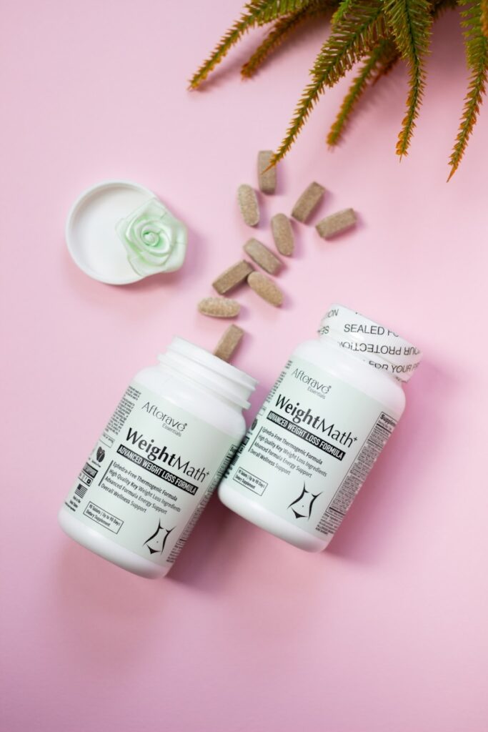 Two bottles of vitamin supplements next to a plant