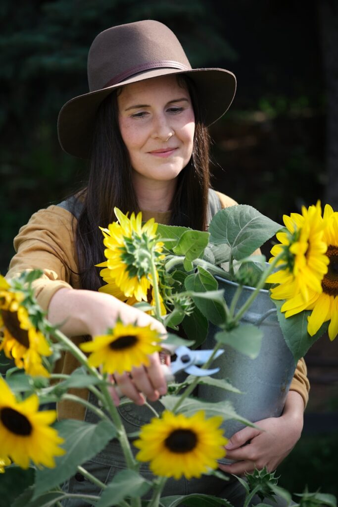 A woman in a hat holding a bucket of sunflowers