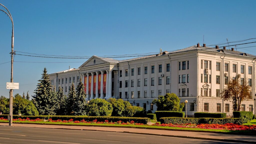 Large, white building with columns and a manicured lawn.