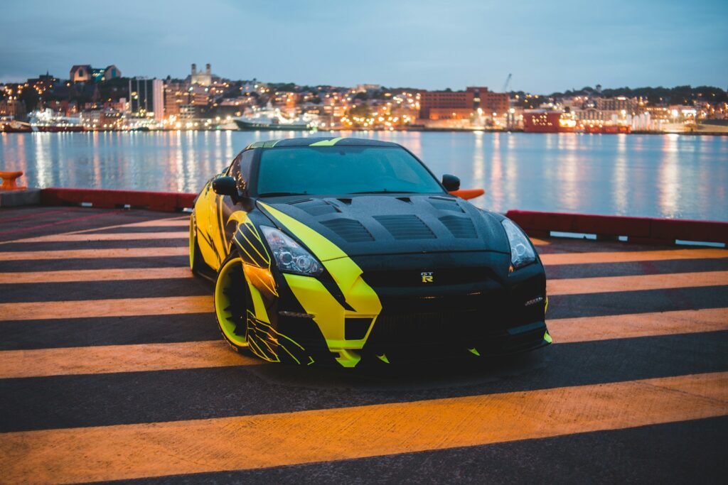 black and yellow lamborghini aventador parked on the side of the sea during daytime
