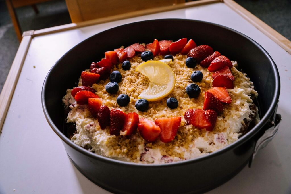 white and blue ceramic bowl with sliced strawberries and blueberries