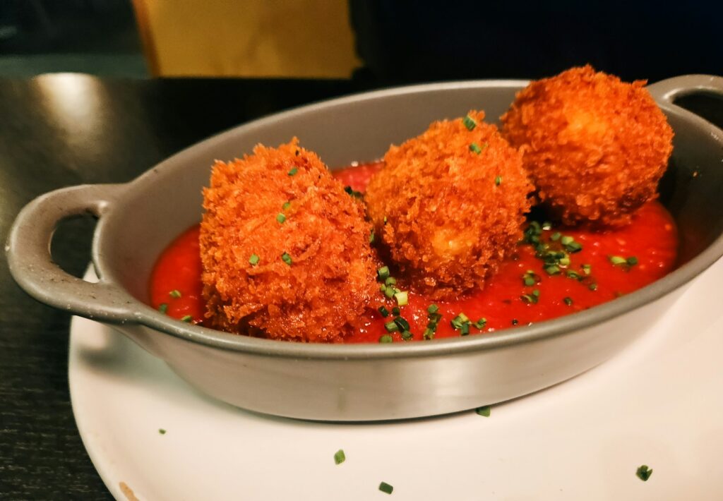 Fried food balls with tomato sauce are served.