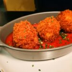 Fried food balls with tomato sauce are served.