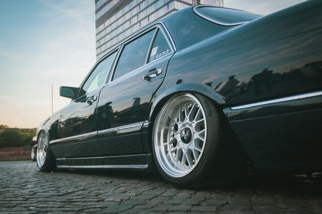 a black car parked on a cobblestone road