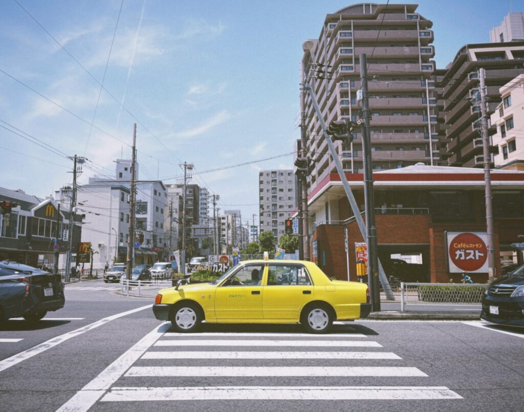 a yellow taxi cab driving down a street next to tall buildings