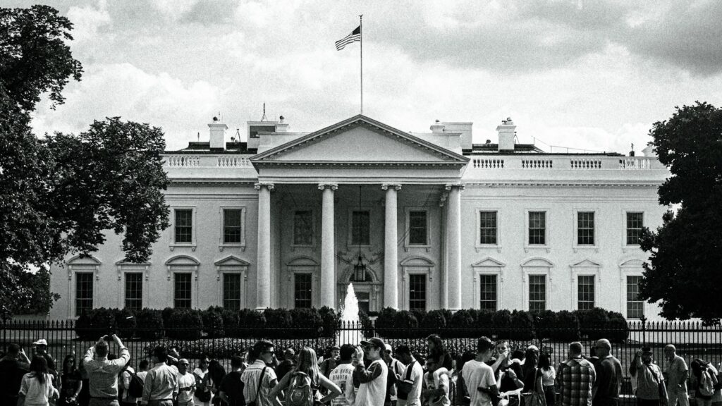 The white house stands with people gathered nearby.