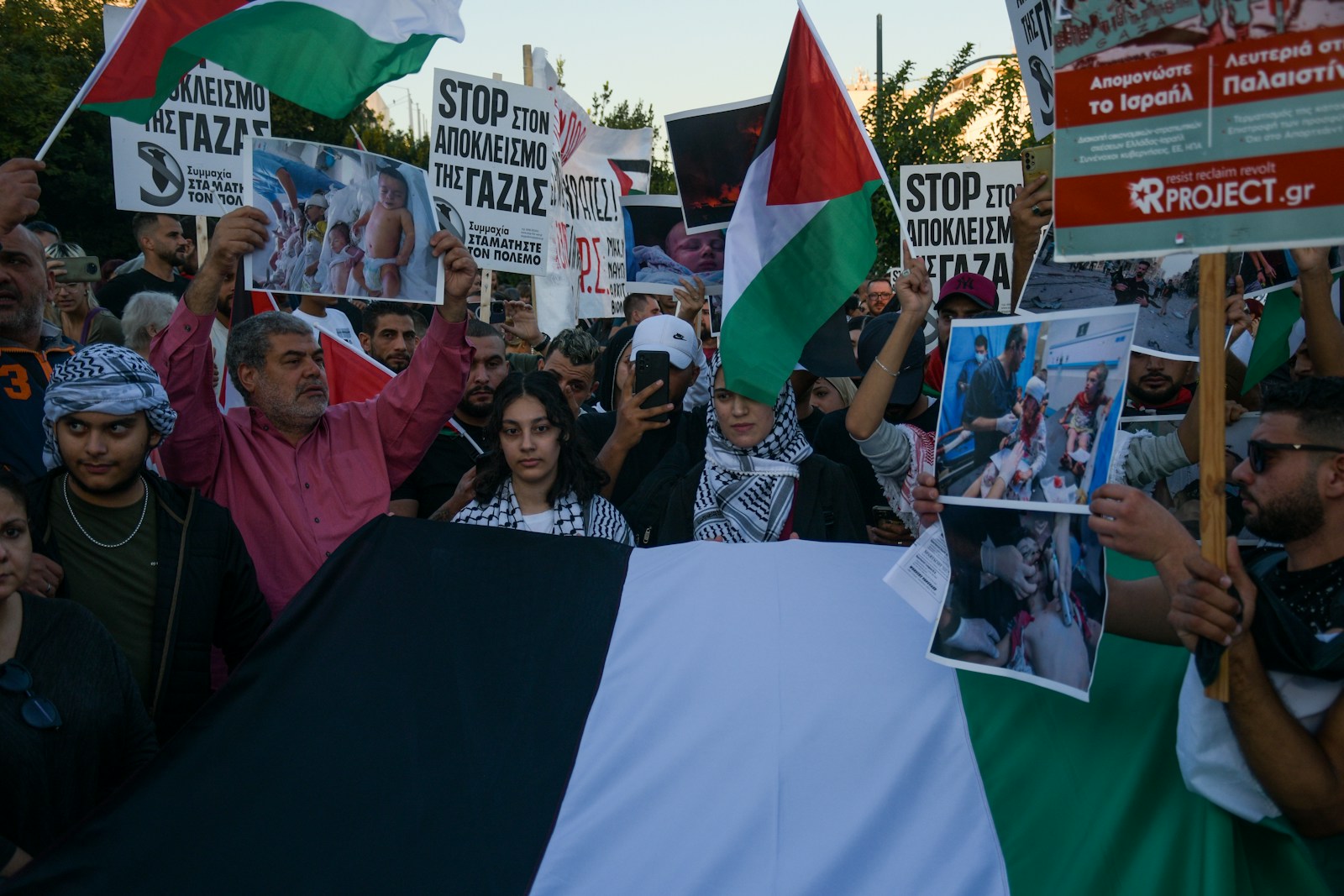 Protesters hold palestinian flags and signs.