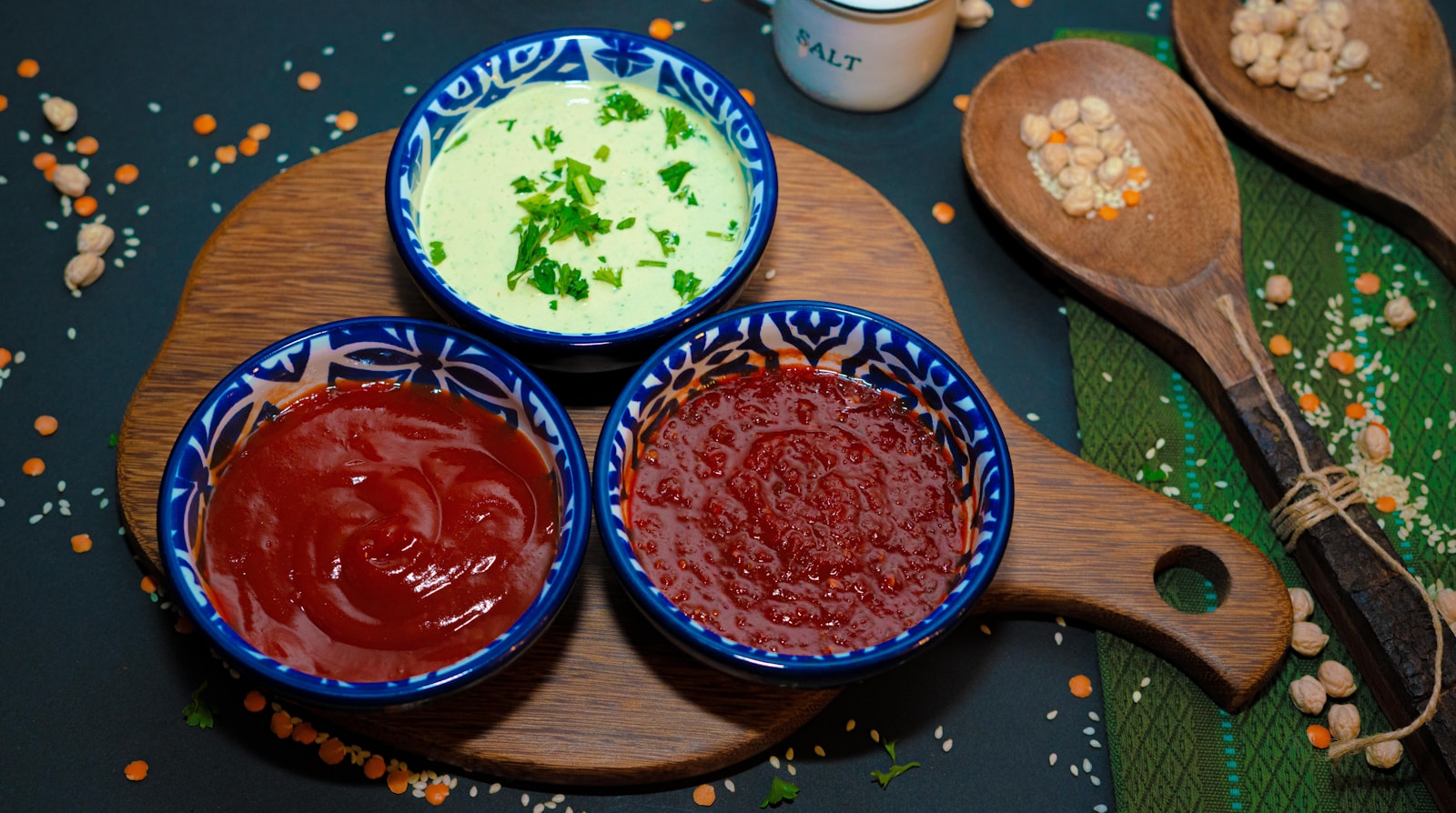 Three small bowls of different colored sauces on a cutting board