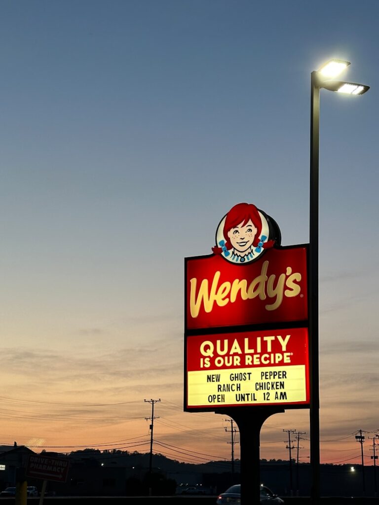 a sign for wendy's restaurant in a parking lot