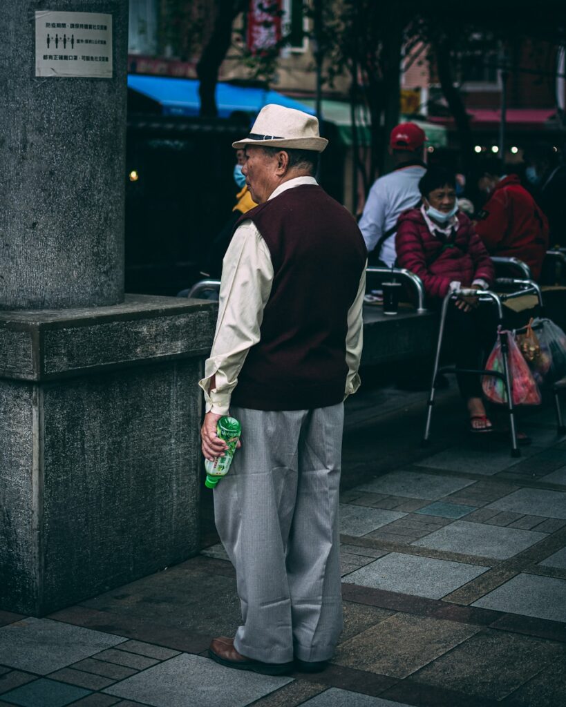 man in white shirt and white pants standing on gray concrete pavement during daytime