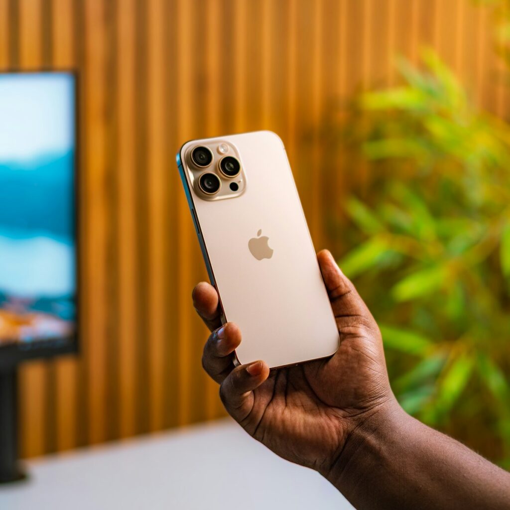 A person holding an iPhone in front of a TV