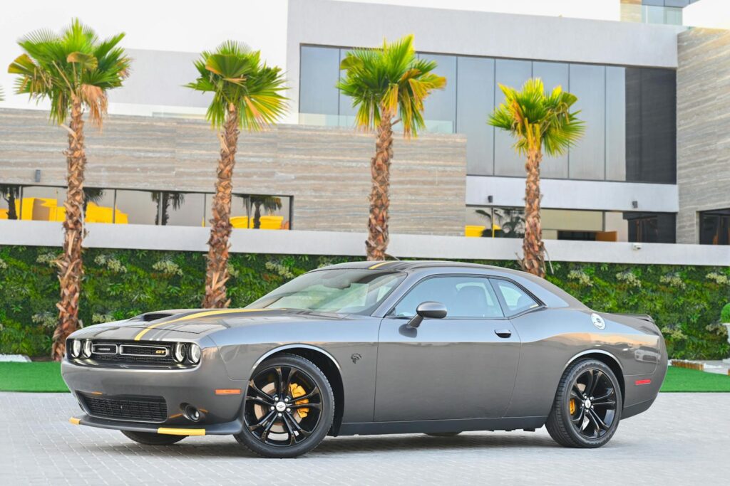 Stylish gray Dodge Challenger parked in a modern Dubai location with palm trees.