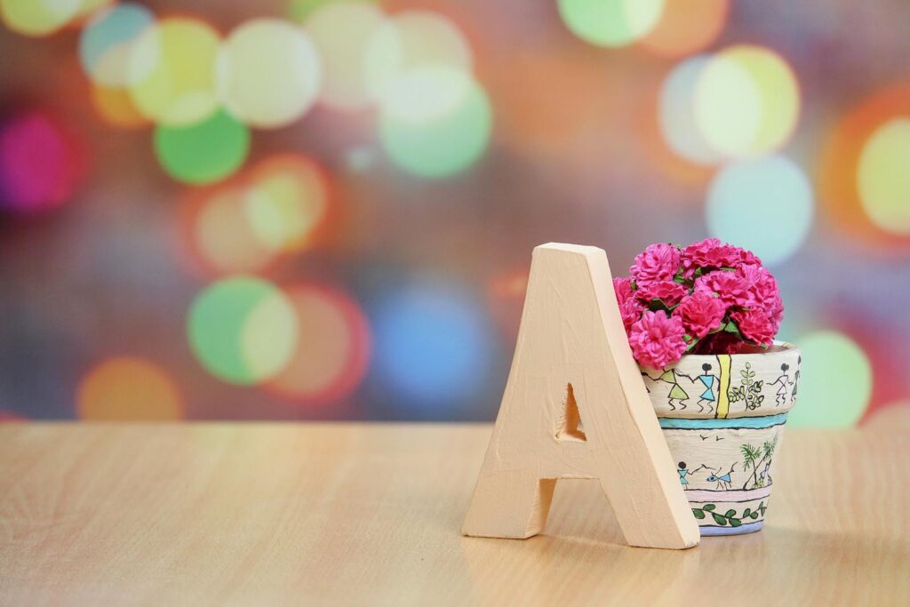 Vibrant bokeh background with floral pot and letter A decoration on table.