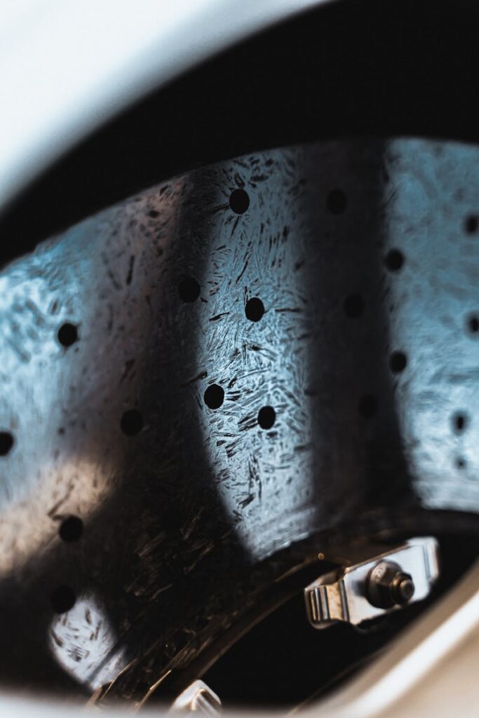 Detailed view of a metallic car brake disc featuring holes and a shiny surface, emphasizing precision engineering.