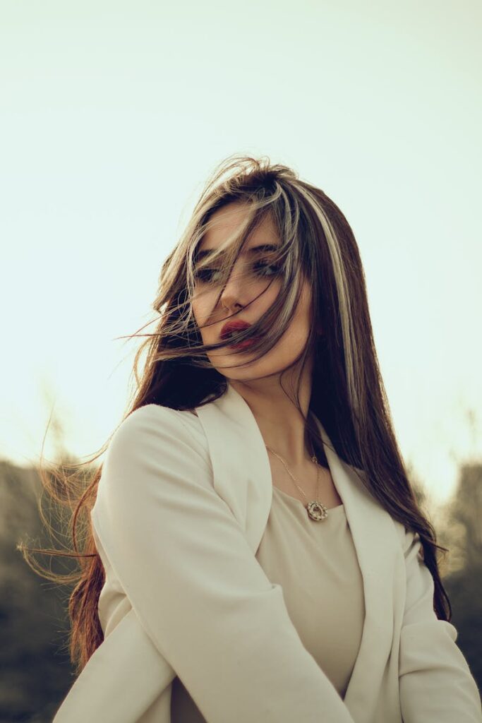 Elegant woman with long hair posing gracefully outdoors in natural lighting.