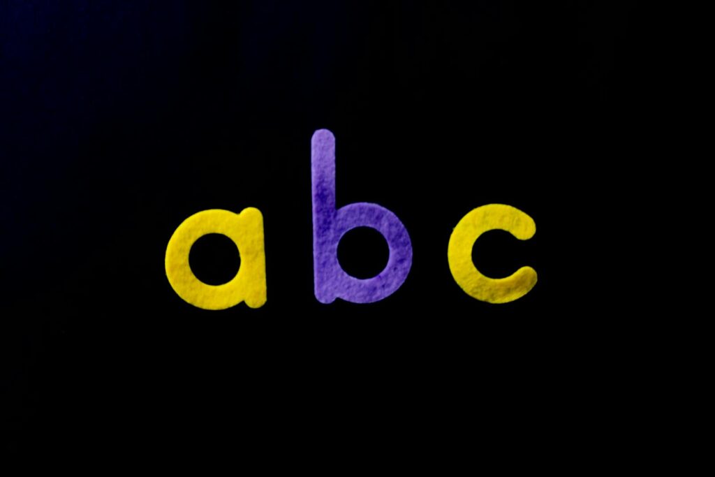 Vivid purple and yellow alphabet letters 'abc' on a black background, perfect for educational themes.