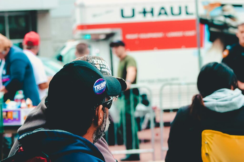Participants at a political rally in Wheeling, WV wearing campaign merchandise with a U-Haul in the background.